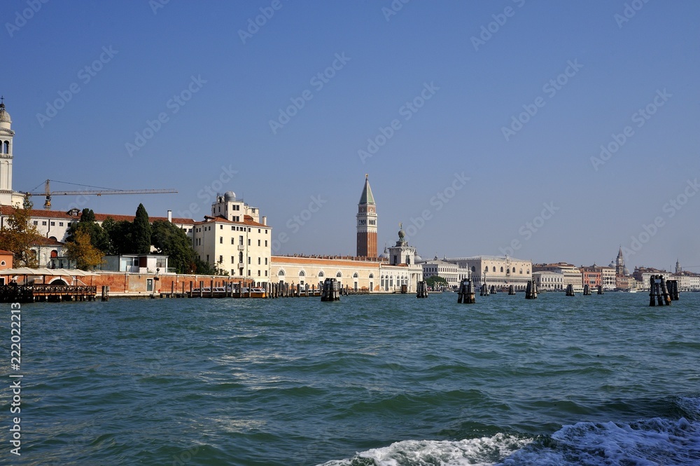 Antica città di Venezia vista dal mare con campanile di Piazza san Marco ed i pali per indicare il percorso delle barche dei turisti nel mare