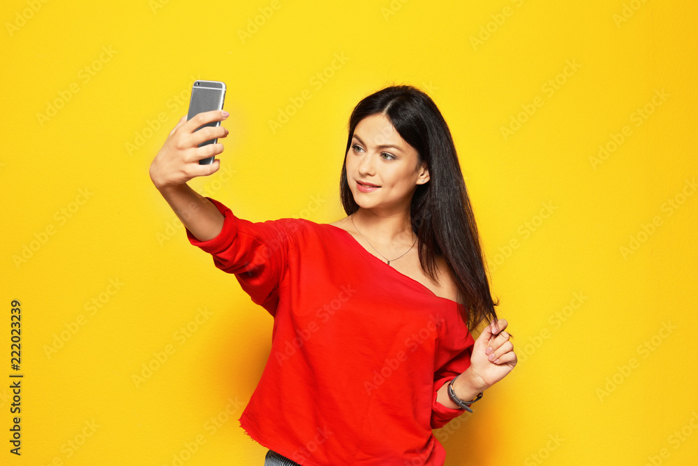 Attractive young woman taking selfie on color background Attractive young woman taking selfie on color background