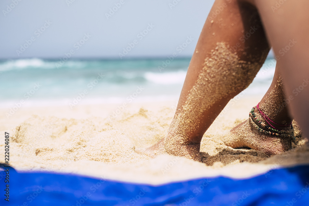 Φωτογραφία close up of beautiful woman legs on the beach making a sunbath relaxing on the sand and looking to the blue waves of the ocean