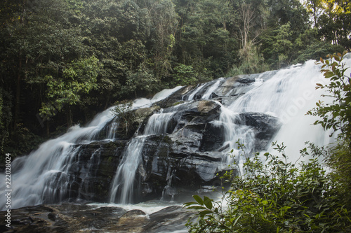 Long exposure of awe-inspiring waterfall surrounded by green vegetation in Mae Klang Luang forest. Chiang Mai, Thailand.