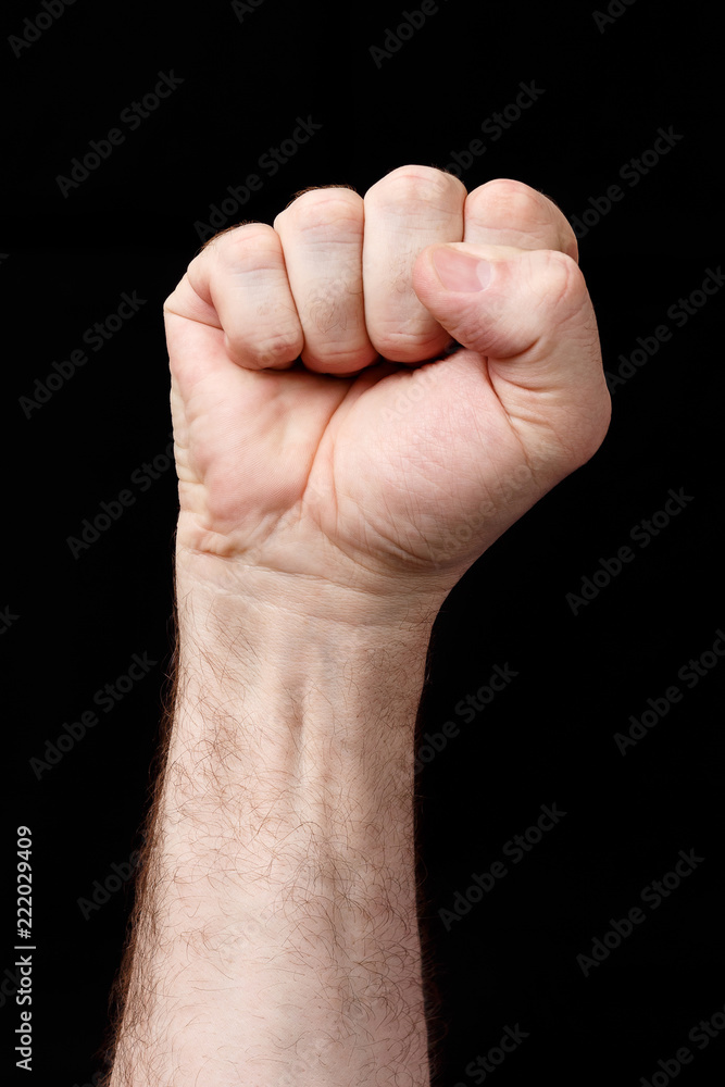 Hand clenched in fist, against a black background Hand clenched in fist, against a black background