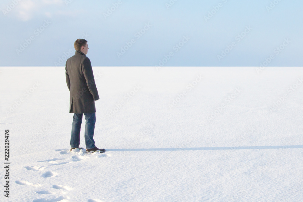 man standing on the shore of a frozen sea downshifting way relaxes on a winter seascape man standing on the shore of a frozen sea downshifting way relaxes on a winter seascape