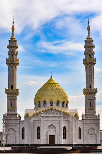 White Muslim mosque with golden domes on a bright day