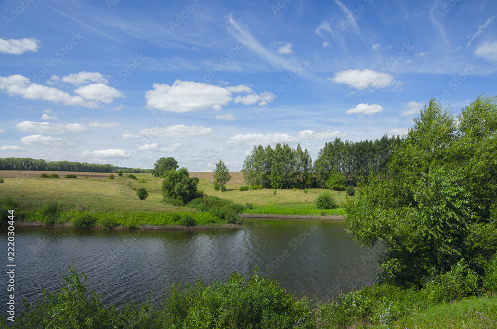 Sunny summer landscape with river,fields,green hills and beautiful clouds in blue sky.Tula region,Russia.