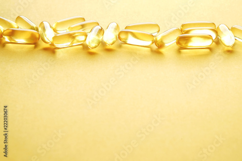 Bunch of omega 3 fish liver oil capsules in row forming pattern background. Close up of big golden translucent pills texture. Healthy every day nutritional supplement. Top view, flat lay, copy space.