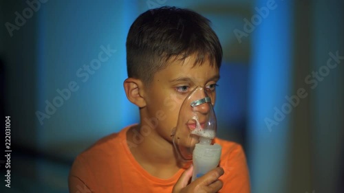 Teenage boy breathes through nebulizer. asthma. inhaler. home medicine.