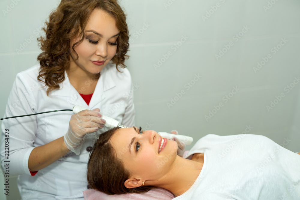 beautiful young girl on ultrasonic face cleaning at a beautician in a beauty salon beautiful young girl on ultrasonic face cleaning at a beautician in a beauty salon