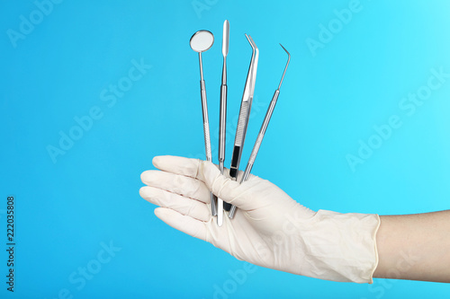 Doctor holding dental equipment in hand on blue background