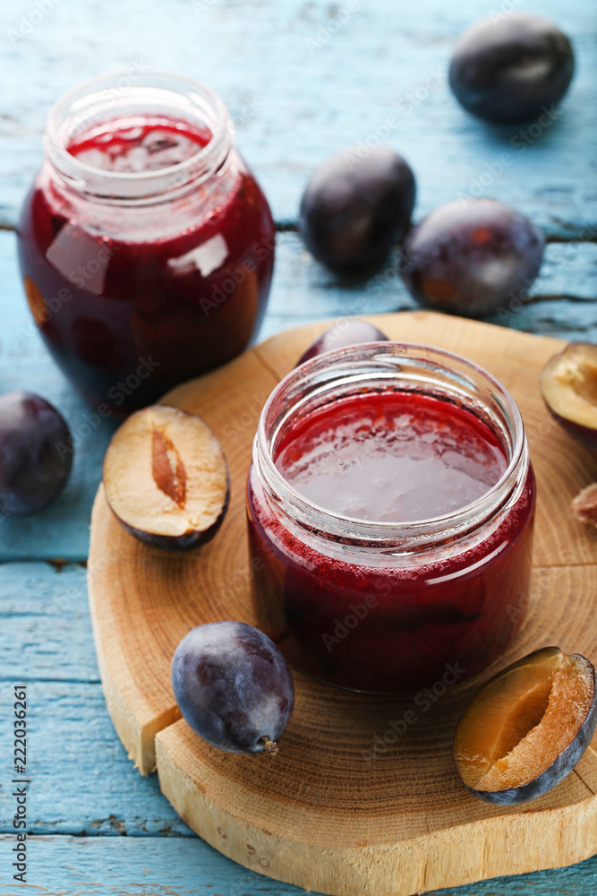 Plum jam in glass jar on blue wooden table Plum jam in glass jar on blue wooden table