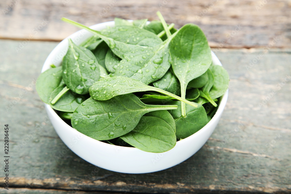 Spinach leafs in bowl on grey wooden table Spinach leafs in bowl on grey wooden table