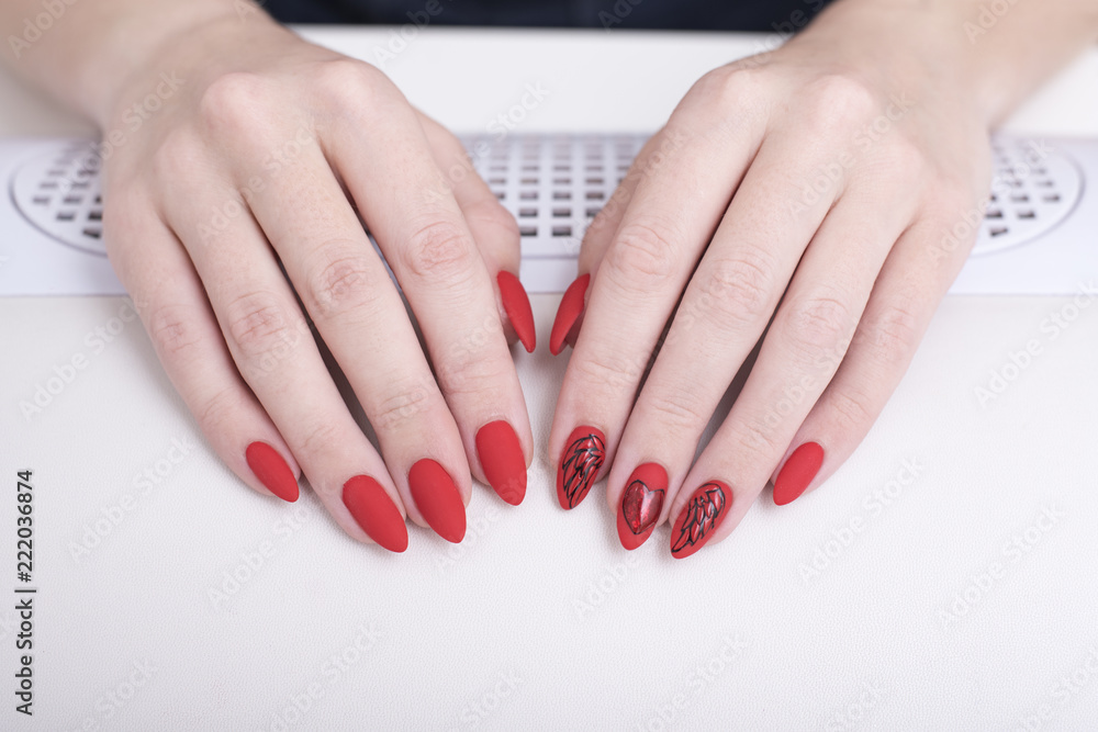 Red manicure with a pattern. Female hands in manicure salon Red manicure with a pattern. Female hands in manicure salon