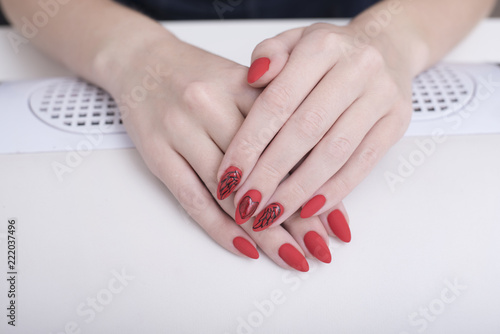 Red manicure with a pattern. Female hands in manicure salon