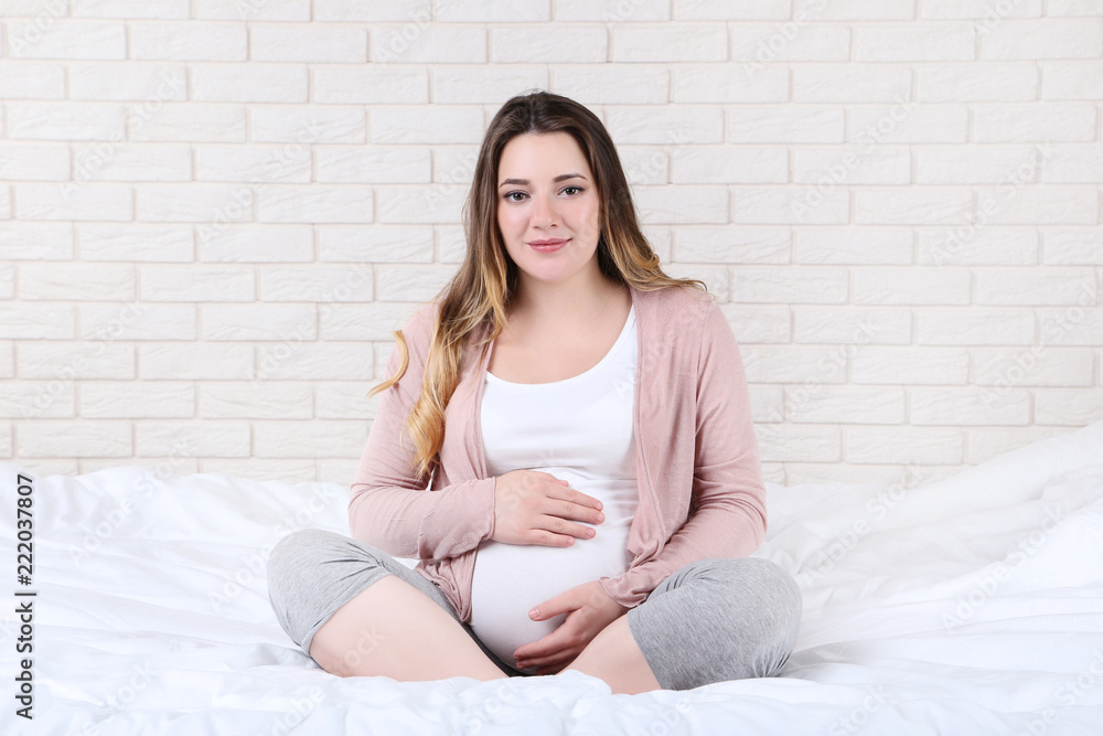 Beautiful pregnant woman sitting on bed Beautiful pregnant woman sitting on bed