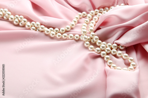 Pearl necklace on pink satin fabric