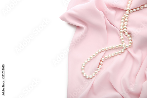 Pearl necklace with pink satin fabric on white background