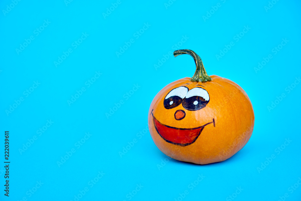 Funny Halloween concept. Cheerful pumpkin with smile face on a blue background Funny Halloween concept. Cheerful pumpkin with smile face on a blue background