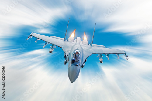 Combat fighter jet on a military mission with weapons - rockets, bombs, weapons on wings, at high speed with fire afterburner engine nozzles, flies in clouds motion blur.