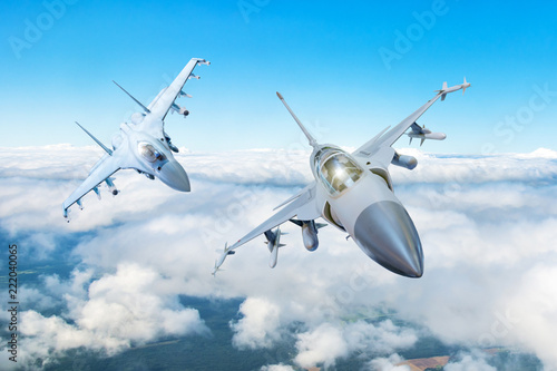 Fototapeta Naklejka Na Ścianę i Meble -  Pair of combat fighter jet on a military mission with weapons - rockets, bombs, weapons on wings flies high in the sky above the clouds.