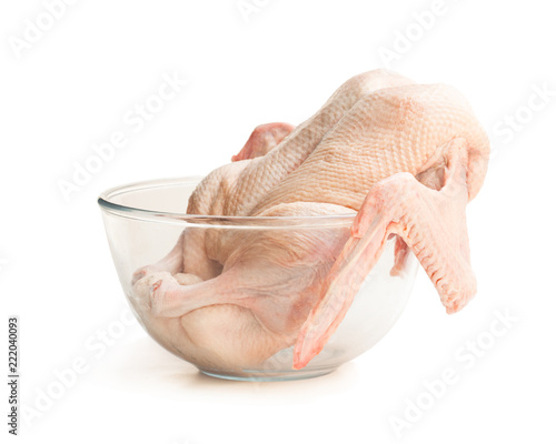 Raw whole duck in clear glass bowl isolated on white background. Ready for cooking.