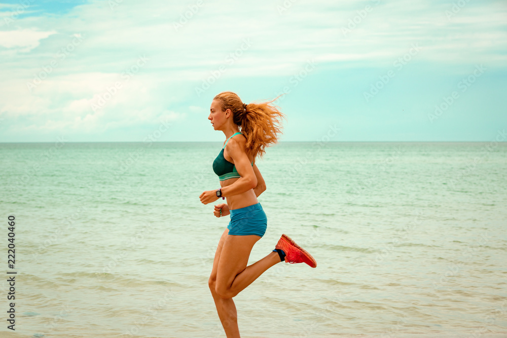 Naklejka premium Beautiful sportive woman running along beautiful sandy beach, healthy lifestyle, enjoying active summer vacation near the sea