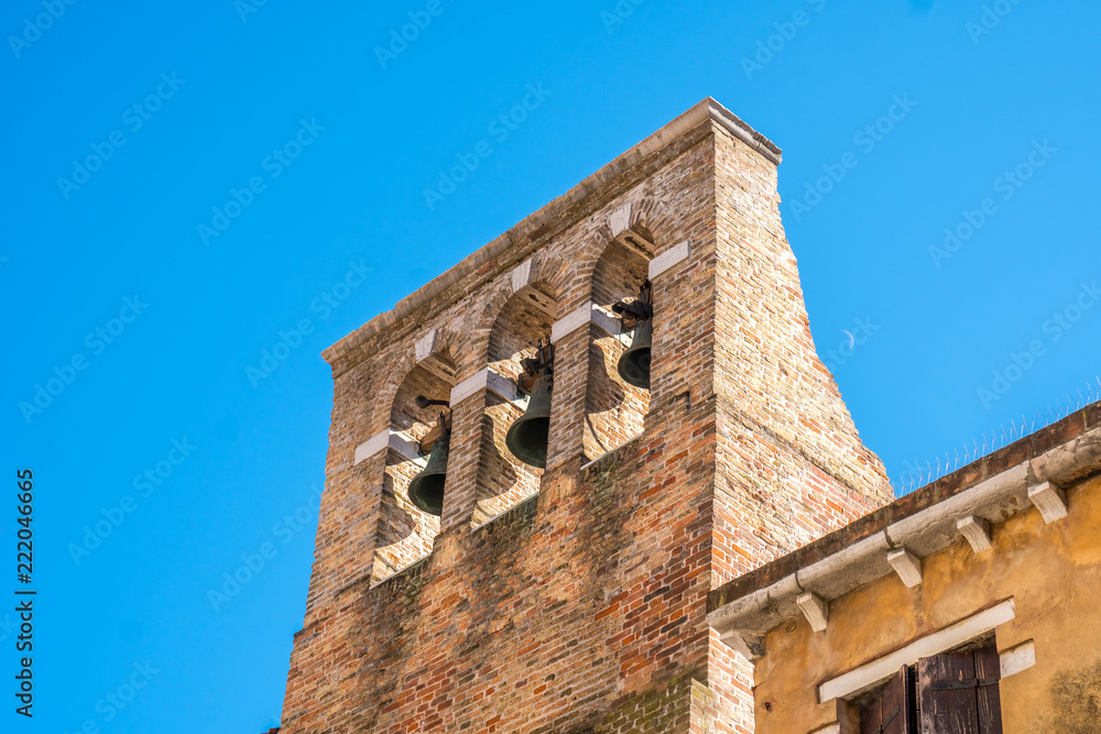 red brick bell tower with three metal bells in Venice, Italy