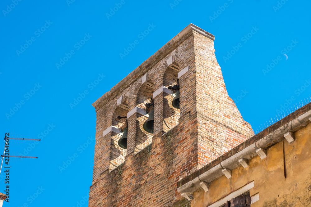 red brick bell tower with three metal bells in Venice, Italy