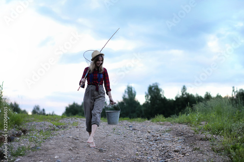 Girl by the river with a fishing rod