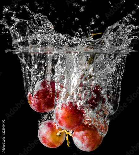 A cluster of grapes dopped into liquid creating beautiful splash