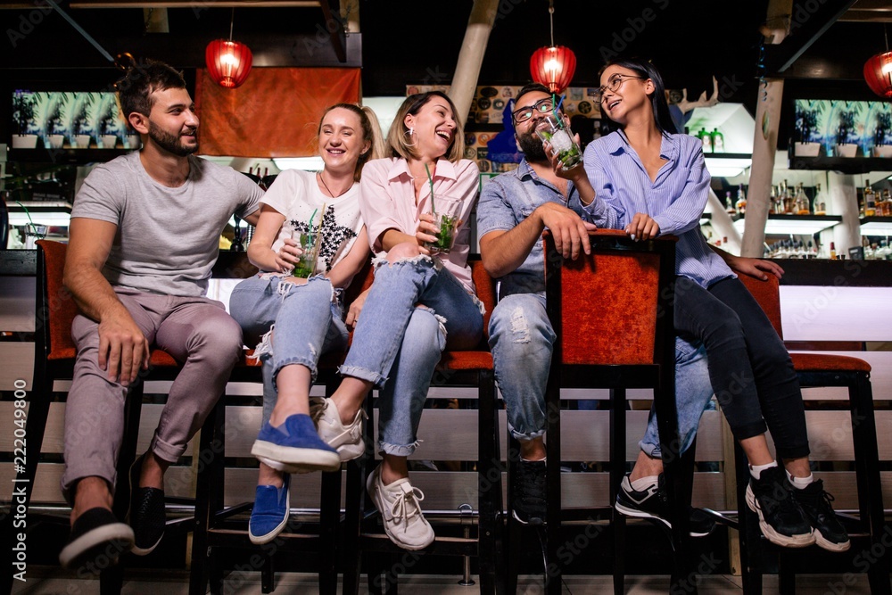 Plakat Pięciu wesołych przyjaciół siedzi przy barze, rozmawiając i śmiejąc się ze sobą