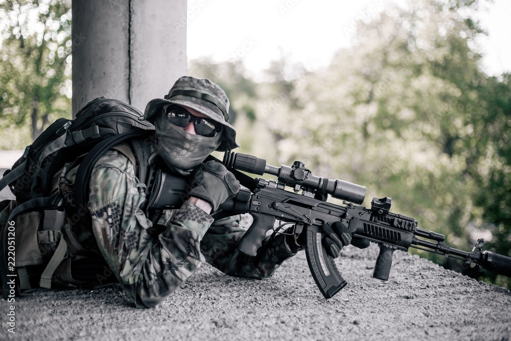 Fototapeta premium Military sniper took a firing position in the destroyed, abandoned building of the city. Urban warfare, urban warfare
