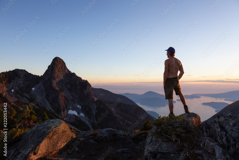 Fototapeta premium Man on top of a mountain enjoying the beautiful view during a vibrant summer sunset. Taken in Howe Sound, near Vancouver, BC, Canada.