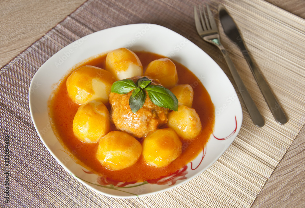 meatball and potatoes in tomato sauce decorated with basil leaf