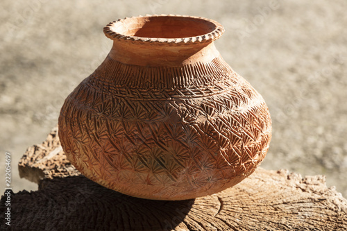 clay potery with the native pattern placed on old wooden table on light and shade beautifully. photo