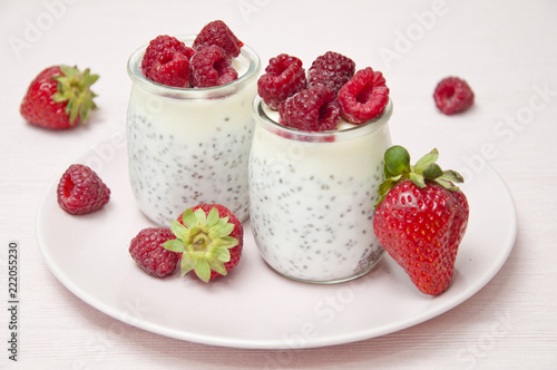 fresh natural yoghurt with sage seeds decorated with strawberries and frozen raspberries