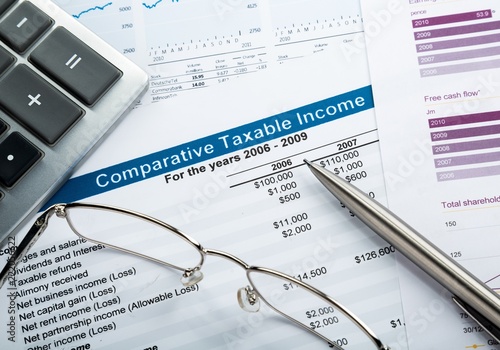 Calculator, Glasses And Pen On Comparative Taxable Income Report photo