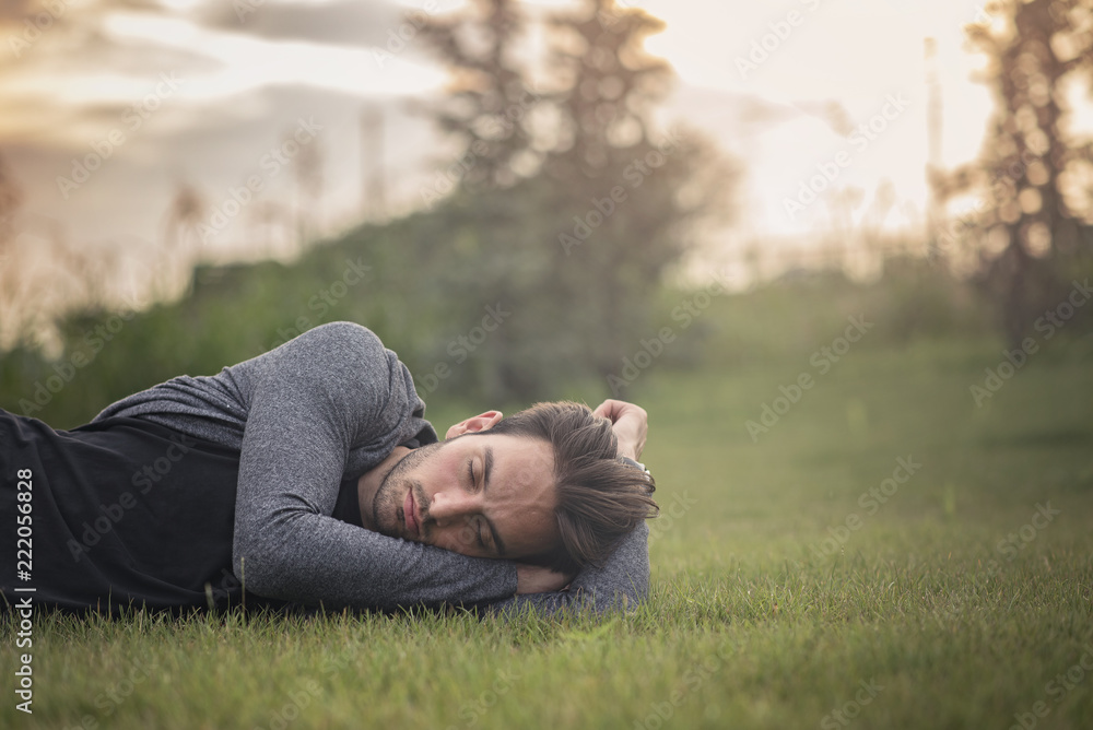 Young handsome man sleeping on the grass in a park, having a nice dream Young handsome man sleeping on the grass in a park, having a nice dream