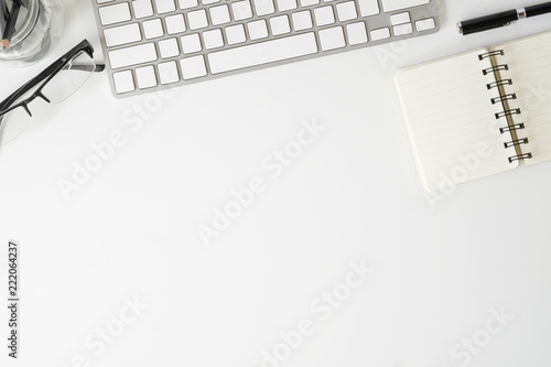 Topview office desk keyboard computer and glasses with notebook paper on white table with copy space.