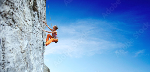Photographie young slim woman rock climber climbing on the cliff