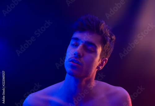 Portrait young man shirtless expresive meditating high sotoned emotion with red and blue light photo