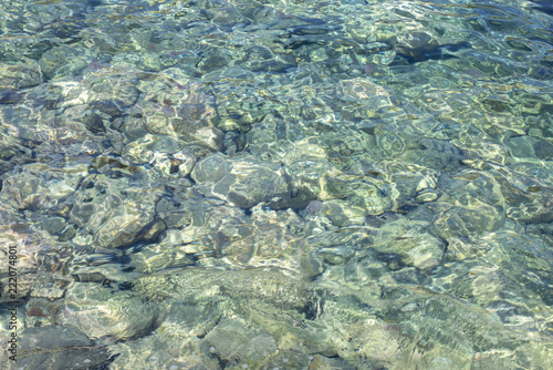 Fototapeta Naklejka Na Ścianę i Meble -  Clear Ocean Water Flowing Under Rocks for Backgrounds