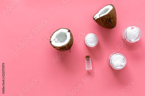 Cosmetics based on coconut oil. Oil in small bottle, cream, coconut pulp, half of coconut with shelf on pink background top view copy space © 9dreamstudio
