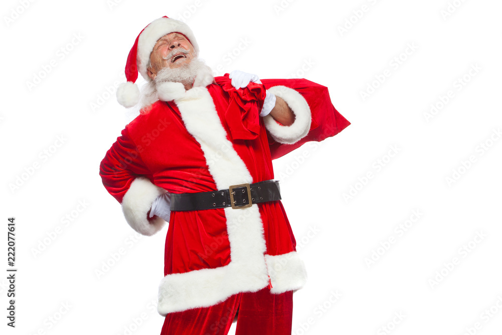 Christmas. Santa Claus is suffering from back pain and holds a red bag with gifts on his back. Isolated on white background. Christmas. Santa Claus is suffering from back pain and holds a red bag with gifts on his back. Isolated on white background.