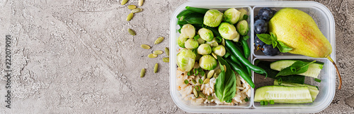 Vegan green meal prep containers with rice, green beans, brussel sprouts, cucumber and fruits. Dinner in lunch box. Banner. Top view. Flat lay