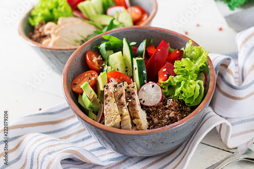 Buddha bowl dish with chicken fillet, quinoa, avocado, sweet pepper, tomato, cucumber, radish, fresh lettuce salad and sesame. Detox and healthy superfoods breakfast bowl concept.