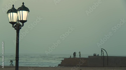 Silhouettes of young Moroccans taking pictures at sunset on the beach of Tarfaya in Morocco photo