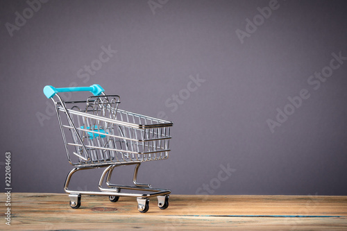 empty supermarket shopping cart on grey background with copy space. marketing, shopping and e-commerce background concept