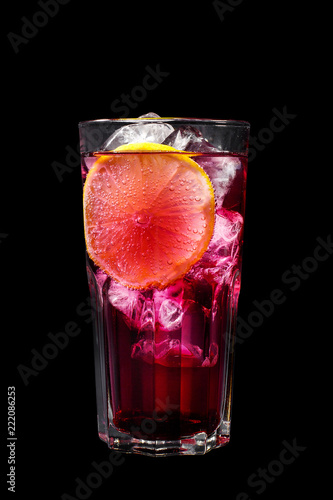 A purple, pink transparent cocktail, refreshing in a tall glass with ice cubes and lemon slice. Side view Isolated black background. Drink for the menu