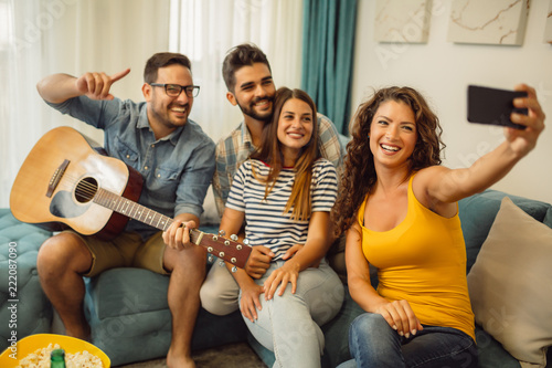 Portrait of group of young friends taking selfie while enjoying at home with guitar, popcorn and beer © Nebojsa