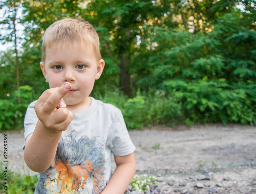The little boy makes an indecent gesture with his hand. The little boy makes an indecent gesture with his hand.