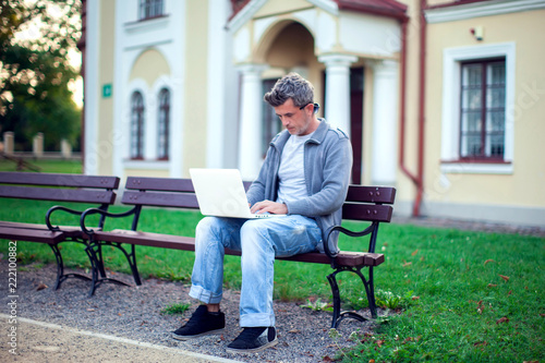 Young man with laptop sitting in the park. People, technology concept